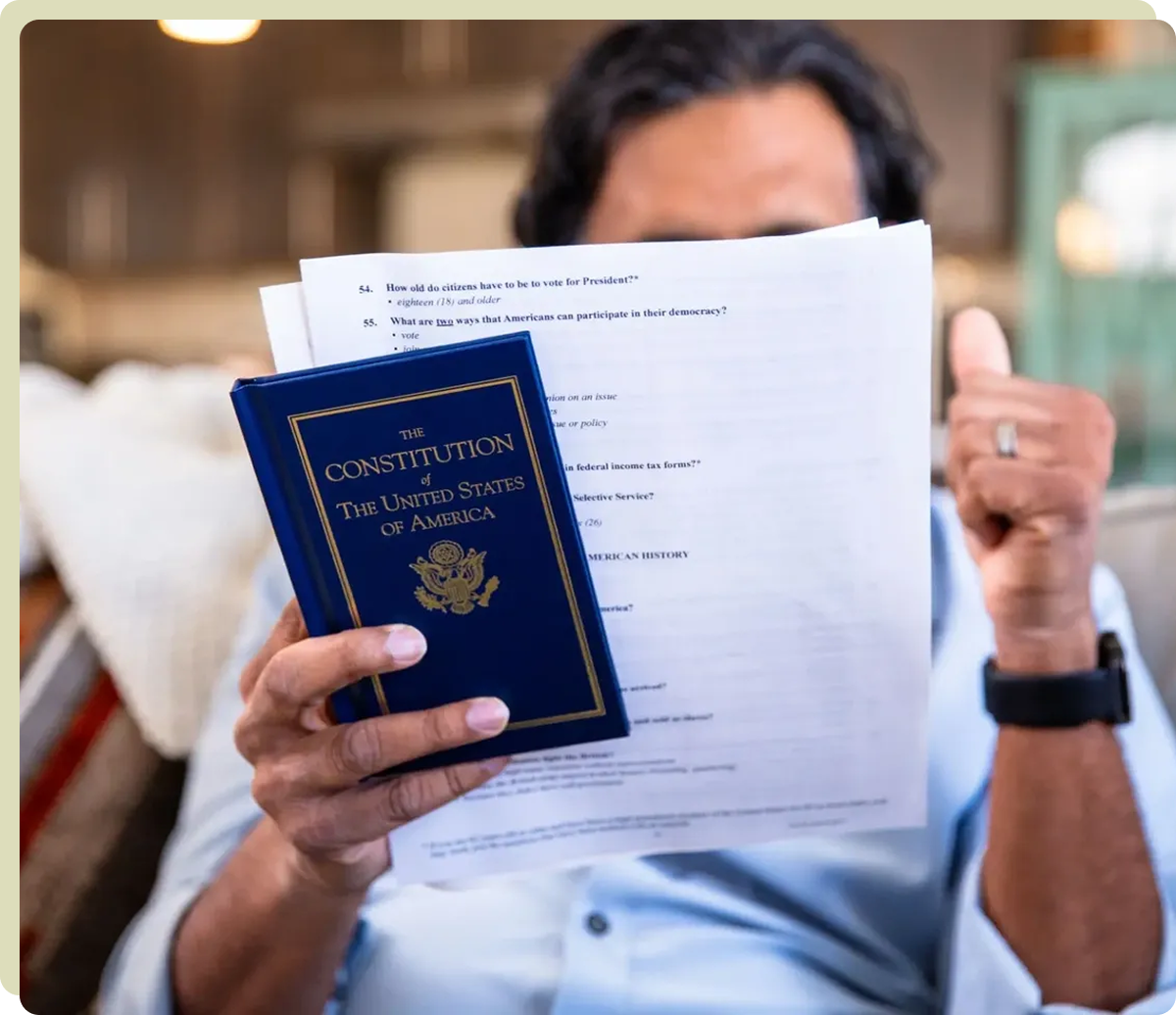 A person holds up a copy of the U.S. Constitution and a worksheet, giving a thumbs up, with their face partially obscured.